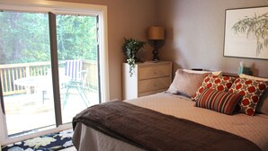 A bedroom with a large bed, a nightstand, a lamp, a potted plant, and a sliding glass door leading to an outdoor area. - Haley Retreat BELLA VISTA LOCATION/BENTONVILLE ADDRESS.ONE MILE TO OZ BIKE LIFT. (Bentonville)