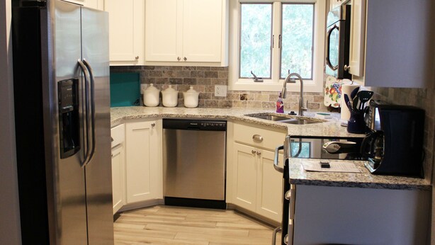 A modern kitchen with white cabinets, a stainless steel refrigerator, a dishwasher, and a window providing natural light. - Haley Retreat BELLA VISTA LOCATION/BENTONVILLE ADDRESS.ONE MILE TO OZ BIKE LIFT. (Bentonville)