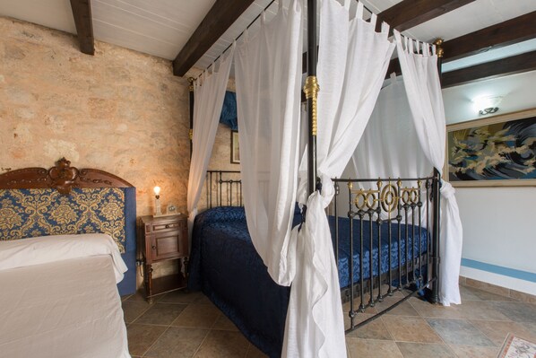 A bedroom with a four-poster bed, a nightstand, and a wall with a patterned wallpaper.