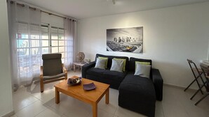 A modern living room with a sofa, a wooden coffee table, and a cityscape painting on the wall. - Beachfront Villa with private pool (La Oliva)