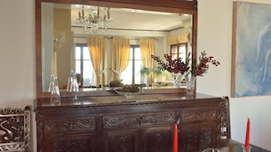 Une commode en bois avec un grand miroir, un vase rempli de baies rouges et un chandelier.