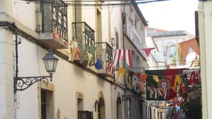 A narrow street with outdoor seating, red chairs, and a café named "SAGRES".