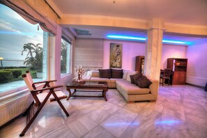 Relax in a spacious living room with a large window offering a view of the outdoors, a comfortable seating area and dining space.