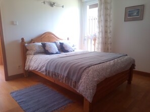 Una camera da letto con un letto di legno, una coperta grigia e un tappeto blu.