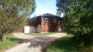 Une maison à deux étages avec une allée en gravier et une terrasse en bois.