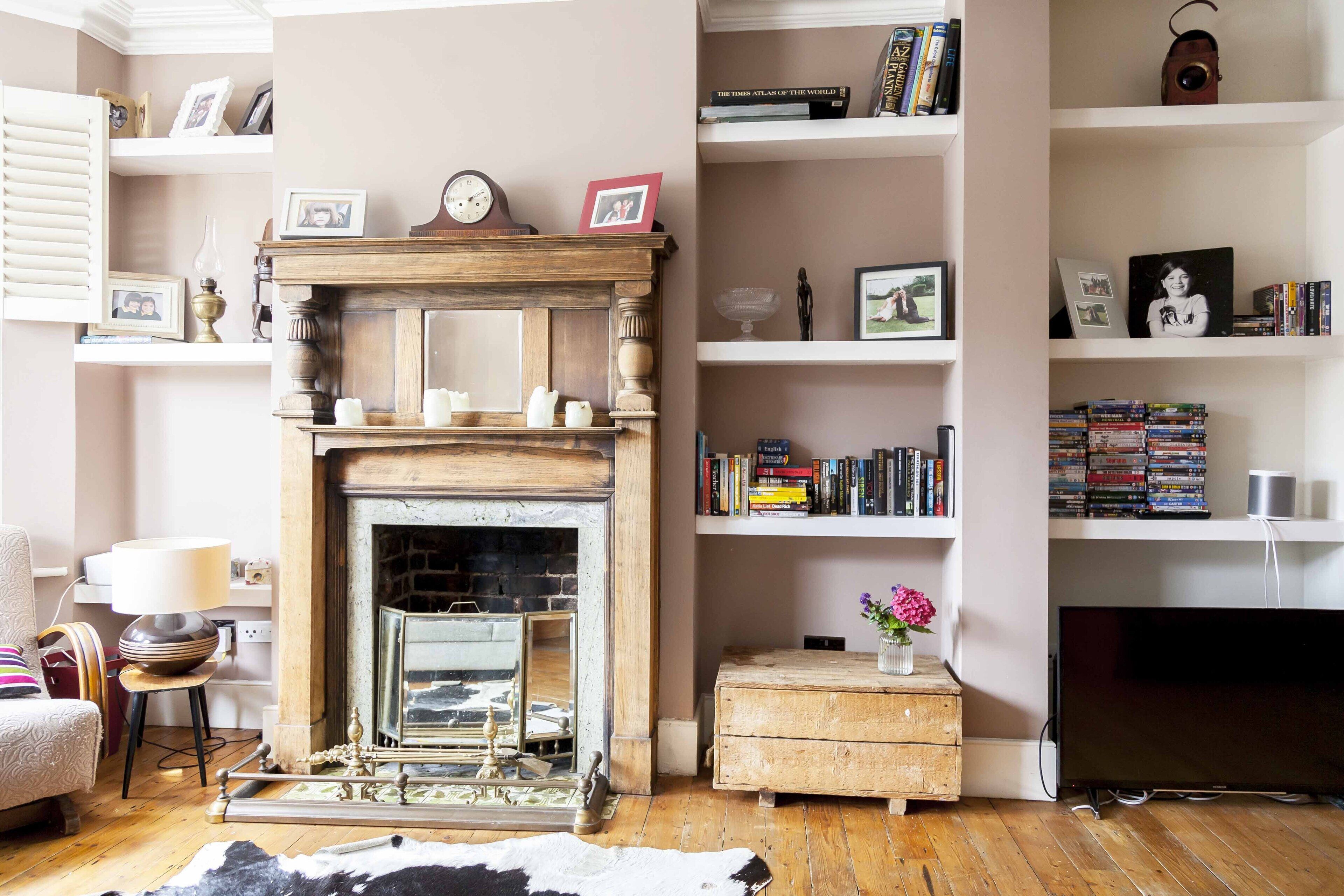 A living room with a fireplace, bookshelves, a television, and a cowhide rug.