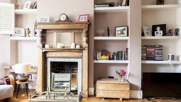 A living room with a fireplace, bookshelves, a television, and a cowhide rug.