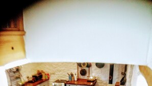 Une cuisine avec une table à manger, des chaises, un réfrigérateur et une pizza posée sur le comptoir.