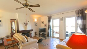 A living room with a sofa, TV, and a ceiling fan. - Luxury 2 Bed Apartment In 5* Villa Sol Village . (Vilamoura)