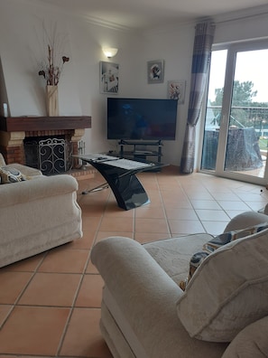Una sala de estar con chimenea, un televisor de pantalla plana y un ventanal grande.