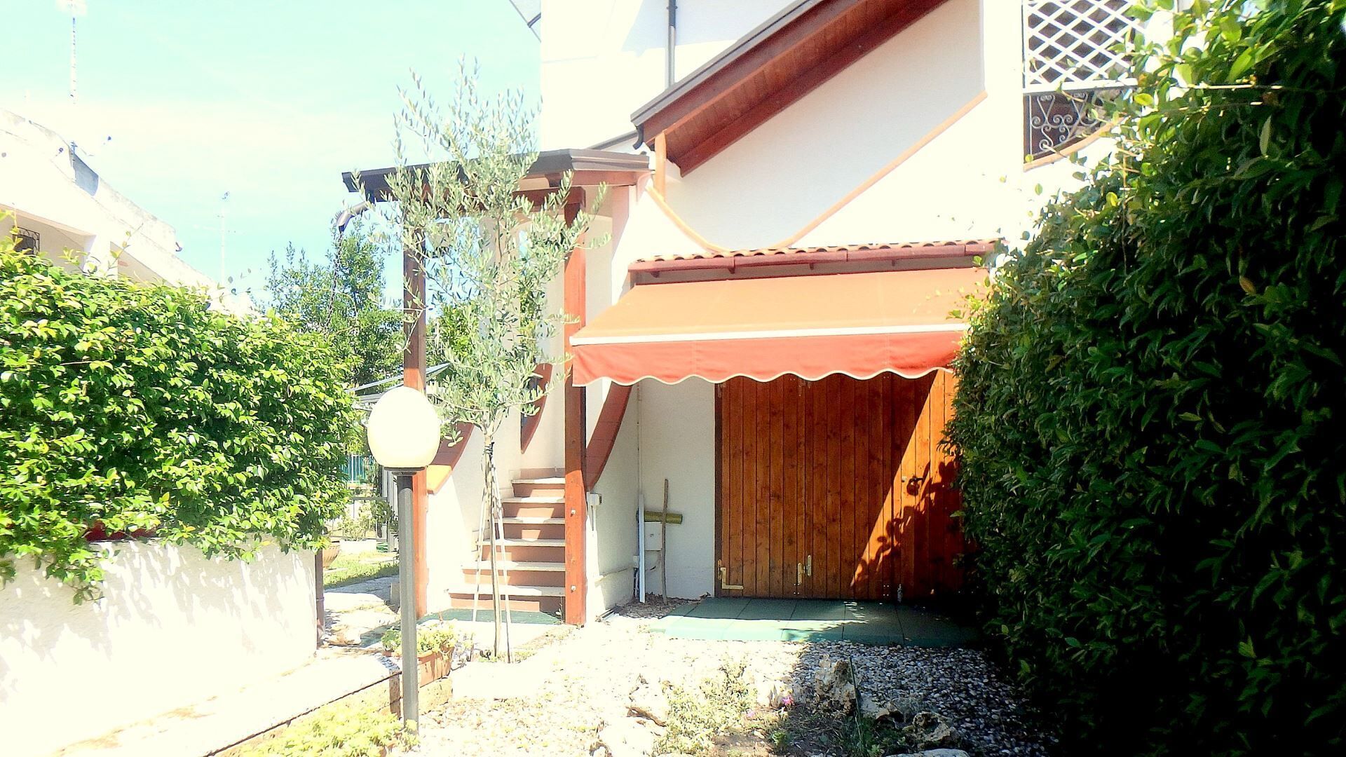 Un immeuble résidentiel avec une porte en bois, un petit escalier et un auvent rouge.
