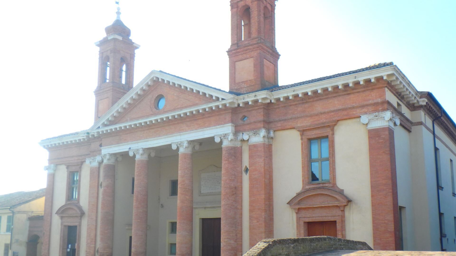 A historic building with a central entrance flanked by columns, a bell tower, and a clock.