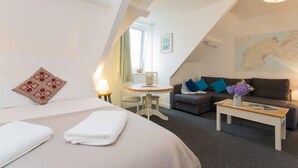A hotel room with a bed, a small table, a sofa, and a map on the wall.