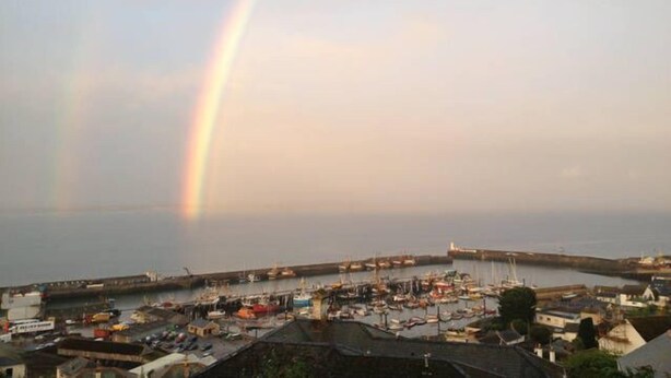 A coastal town with a harbor, boats, and a rainbow.