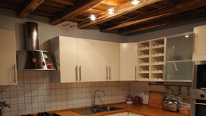 Uma cozinha com armários de madeira, coifa em aço inoxidável, bancada de madeira e painel de azulejos.
