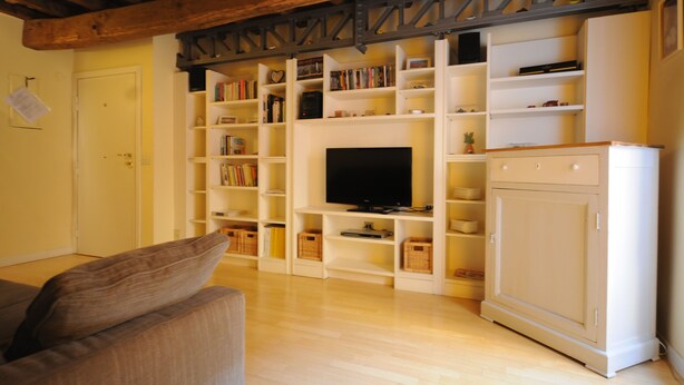 Uma sala de estar com televisão, estantes e um armário.