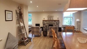 A cozy living room with a stone fireplace, wooden furniture, and a ladder shelf.