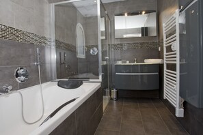 A modern bathroom with a bathtub, shower, and vanity. - Apartment Rooftop Villefranche-Sur-Mer (Villefranche-Sur-Mer)