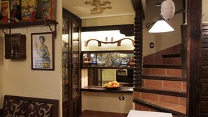 A cozy restaurant interior with a wooden staircase, a dining area with a table and chairs, and a shelf with various items.