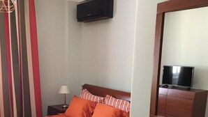 A bedroom with a bed, a nightstand, a lamp, a TV on a stand, and a window with curtains. - Athens Modern Apartment next to Syntagma Square  (Athina)