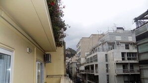 A narrow urban street with a building on the left featuring a glass door and a small table with chairs. - Athens Modern Apartment next to Syntagma Square  (Athina)
