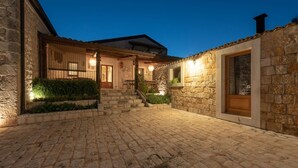 A stone building with a courtyard, a wooden door, and a staircase leading to a covered area. - Casa Natia - Luxury Villa with pool (Modica)