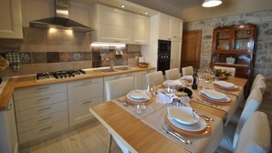 A modern kitchen with a central island, stainless steel appliances, and a dining area set for six. - Casa Natia - Luxury Villa with pool (Modica)
