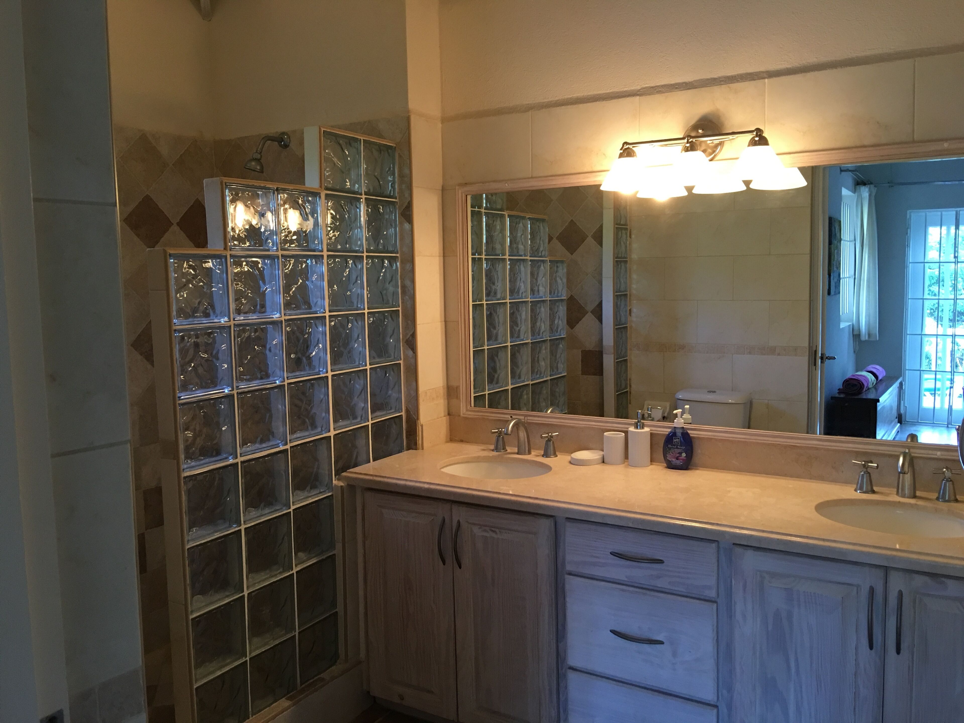A bathroom with two sinks, a large mirror, and a glass shower enclosure.