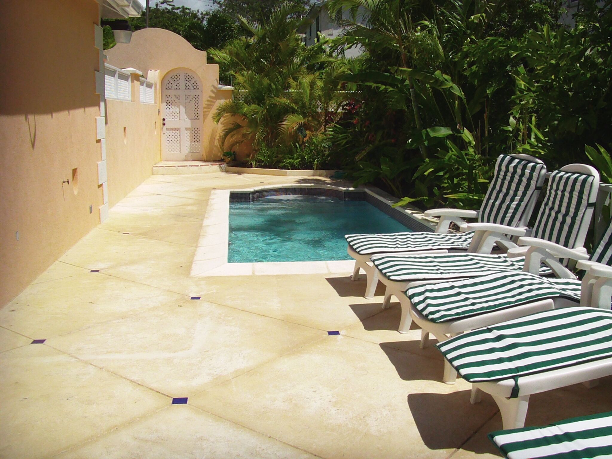 Una piscina con sillones de descanso y un suelo de baldosas.