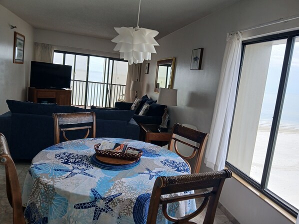 Un salon avec une table ronde, des chaises, un canapé, un téléviseur et un balcon avec vue.