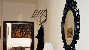 Una sala de estar con un sofá, una mesa de centro de vidrio con revistas, una lámpara y un espejo grande.