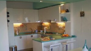 A compact kitchen with white cabinets, a central island, and a bar stool.