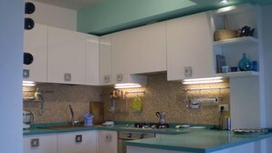 A compact kitchen with white cabinets, a blue countertop, and under-cabinet lighting.