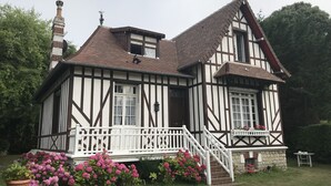 Et bindingsværkshus i Tudor-stil med et stejlt tag, hvidt og mørkt træværk og en lille veranda med et hvidt gelænder.