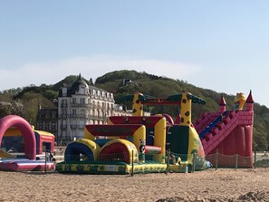 An inflatable play area with various structures, including a castle and a slide, set against a backdrop of a historic building and a hill. - Charming villa in Houlgate beach 100m, 5mn walk from linen shops (Houlgate)