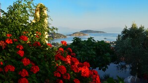 Un paysage côtier avec des fleurs rouges au premier plan et une vue sur la mer et les îles en arrière-plan.