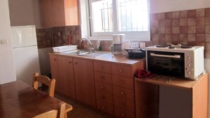 Une cuisine de taille réduite, dotée de meubles en bois, d’un évier, d’une cuisinière et d’un four à micro-ondes.