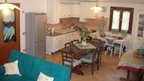 A compact living space with a kitchenette, dining area, and a sofa. - House / Villa - STINTINO (Stintino)