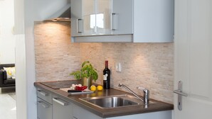 Una cocina moderna con armarios azul claro, un lavamanos de acero inoxidable y un respaldo de ladrillo.