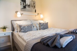 Un letto rifatto con cura, coperto da biancheria da letto floreale e dotato di due lampade da lettura fissate alla parete.