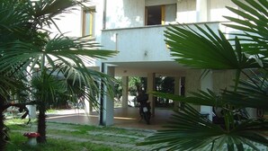 A two-story building with a covered outdoor area, a motorcycle parked outside, and a mushroom-shaped garden ornament.