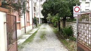 A narrow alleyway with a gravel path, metal gates, and a sign indicating private property.