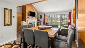 Un coin repas avec une table et des chaises en bois, une cheminée et un téléviseur.