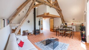 Un acogedor espacio tipo loft con vigas de madera a la vista, una chimenea, comedor y cocina.