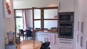 A modern kitchen with a central island, bar stools, a built-in oven, and a microwave. - Peacefull villa, (beautiful tip of Penn Al Lann, sea 50m), Carantec, Britanny.  (Carantec)