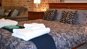 A neatly made bed with a patterned bedspread, a wooden headboard, and a stone wall with a framed picture above it. - Recently refurbished barn, close to coast, pet friendly with a secure garden. (Lessingham)