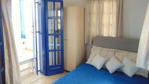 A bedroom with a bed, a wardrobe, and a door leading to an outdoor area. - Sunny with sea view apartment (Santorini)
