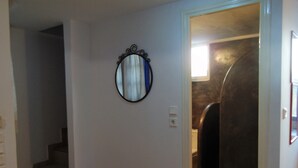 A hallway with a mirror on the wall, a door leading to a bathroom, and a staircase. - Sunny with sea view apartment (Santorini)