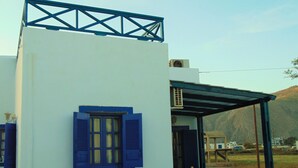 A white building with blue shutters and a balcony. - Sunny with sea view apartment (Santorini)