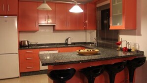 Eine Küche mit roten Schränken, einer Granit Arbeitsplatte und einer integrierten Bar mit schwarzen Hocker.